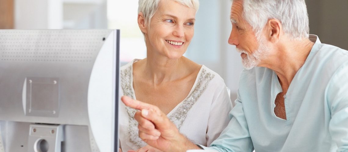 A senior man teaching a senior woman how to use the computer